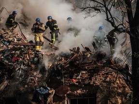 Ukrainian firefighters works on a destroyed building after a drone attack in Kyiv on October 17, 2022, amid the Russian invasion of Ukraine. - Ukraine officials said on October 17, 2022 that the capital Kyiv had been struck four times in an early morning Russian attack with Iranian drones that damaged a residential building and targeted the central train station.