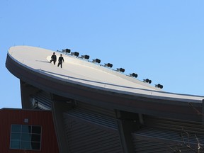 Workers walk on the roof of the Scotiabank Saddledome on Wednesday.