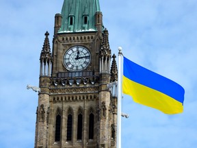The flag of Ukraine is seen alongside Parliament Hill's Peace Tower in Ottawa, on Saturday, Feb. 26, 2022.
