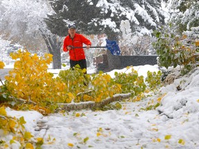 John Fisher shovels his walk as the city was hit with a heavy snowfall overnight in Calgary on Saturday, October 22, 2022.