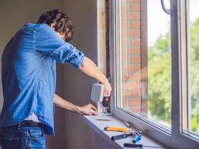 Man in a blue shirt does window installation.