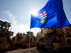 An Alberta flag is surrounded by heavy pipeline machinery in Edmonton.
