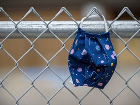 A child's mask is left on a fence outside a school yard on Tuesday, September 15, 2020.