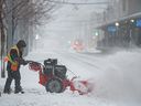 A worker clears snow from sidewalks in downtown Calgary on Wednesday.