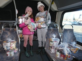 Sisters Claire, 10, (L) and Lucie Fleming, 12, pose with some of the food items donated Saturday, Nov. 19, 2022, during the 30th annual Stuff-a-Bus in support of the Calgary Food Bank.