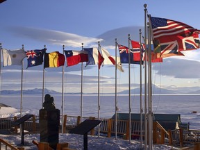 Today in history in 1929, U.S. Admiral Richard Byrd became the first man to fly over the South Pole. Flags of the original 12 signatory nations of the Antarctic Treaty fly next to a bust of Byrd at McMurdo Station on October 21, 2005 in Antartica.