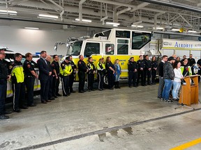 Paramedic Jayme Erickson is comforted by family, friends and colleagues as he speaks to the media at a fire hall in Airdrie on Tuesday.