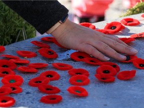 Calgarians place their poppies at the eternal flame outside the Military Museums during Remembrance Day in Calgary on Friday, November 11, 2022.