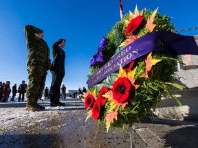 Soldiers salute after placing their poppies at the eternal flame outside the Military Museums on Remembrance Day in Calgary, Friday, Nov. 11, 2022.