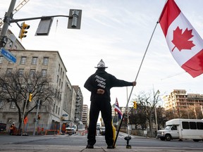 A Freedom Convoy supporter stands at the curb in front of Library and Archives Canada, the site of the Public Order Emergency Commission in Ottawa on Wednesday, Nov. 2, 2022.