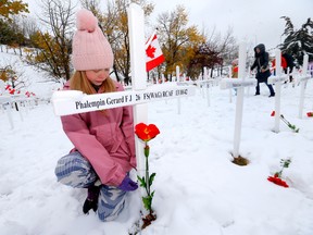 Student Elizabeth Groenebeld, 10, from Delta West Academy, along with teachers, fellow students and their families, continues the 10-plus year tradition of placing poppies at the Field of Crosses along Memorial Drive in Calgary on Sunday, Oct. 23, 2022.