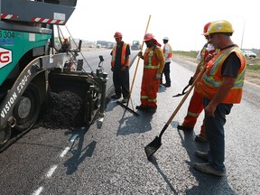 Part of the road crew tasked with paving the twinning of Metis Trail work on freshly pressed ashphalt in northeast Calgary on Friday, August 10, 2018. Temperaturs can easily reach 120-140 F or more directly behind the machine. It is one of the hottest jobs on one of the hottest days of the year and all time in Calgary. Jim Wells/Postmedia