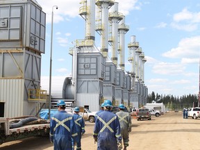 Employees at the Cenovus Christina Lake oil sands facility, located south of Fort McMurray, walk past steam generators as they start their shift in this May 2012 file photo.