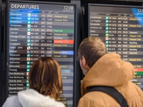 Travellers take a look at the departures information board at Calgary International Airport (YYC) as extreme cold in Calgary and winter conditions in other parts of Canada has caused numerous flight delays and cancellations on Thursday, December 22, 2022.