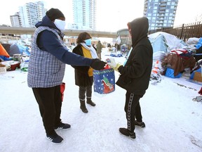 Moses and Jennifer Ndirangu (L) hand out small gifts of clothes and goodies at the Drop In Center in downtown Calgary on Saturday, December 25, 2021.