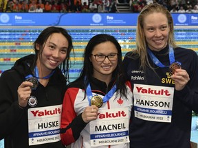 Maggie Mac Neil of Canada, centre Torri Huske of the U.S., left, and Louise Hansson of Sweden display their medals after the women's 100m butterfly final during the world swimming short course championships in Melbourne, Australia, Sunday, Dec. 18, 2022. Mac Neil won gold, Huske took silver and Hansson the bronze.