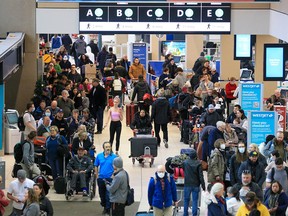 Hundreds of WestJet passengers line up as they wait to rebook cancelled flights at the Calgary International Airport on Tuesday, December 20, 2022. Weather issues across Canada have caused flight delays and cancellations.