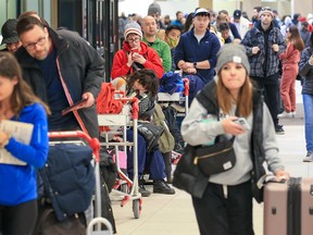 Hundreds of WestJet passengers line up as they wait to rebook canceled flights at Calgary International Airport on Tuesday, Dec. 20, 2022. Weather problems across Canada have caused flight delays and cancellations.