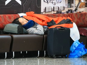 A traveler rests at Calgary International Airport on Tuesday, December 20, 2022. Weather issues across Canada have caused flight delays and cancellations.