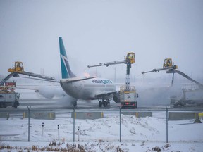 A WestJet Boeing 737 is de-iced at Calgary International Airport on Tuesday, December 20, 2022.  Extreme cold temperatures are forecast in the city for most of the week.