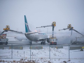 A WestJet Boeing 737 is de-iced at Calgary International Airport on Tuesday, December 20, 2022. Extreme cold temperatures are forecast in the city for most of the week.