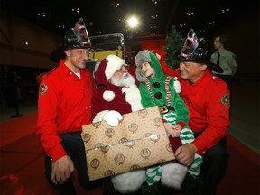 Daxton Brown, 8, was all smiles visiting Santa and firefighters Geoff Dommett and Greg Smigel at the annual Calgary Firefighters Toy Association at the Telus Convention Centre in Calgary on Sunday, December 18, 2022.