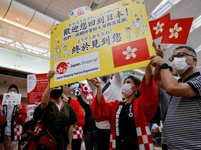 Members from Japan's shopping and tourism companies hold a placard reading 'Welcome back to Japan! We finally met you!' as they greet a group of tourists from Hong Kong upon their arrival at Haneda airport, as Japan gradually opens to tourists after two years of coronavirus disease (COVID-19) restrictions, in Tokyo, Japan, June 26, 2022.