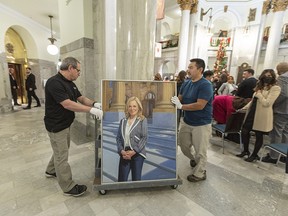 Workers prepare to hang the official portrait of former premier Rachel Notley in the Alberta legislature on Thursday.