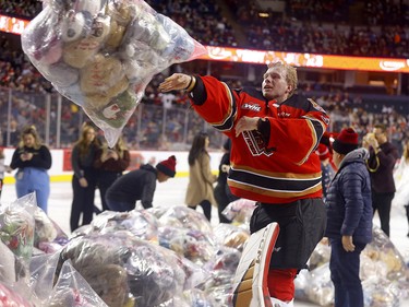Calgary Hitmen players help collect stuffed animals after London Hoilett scored on Moose Jaw Warriors goalie Jackson Unger to unleash the teddy bears during the Calgary Hitmen’s 27th annual ENMAX Teddy Bear Toss at the Scotiabank Saddledome in Calgary on Sunday, December 4, 2022.