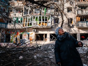 An elderly woman looks on as she stands in front of a residential building damaged by Russian shelling amid the Russian invasion of Ukraine on December 20, 2022 in Kherson.