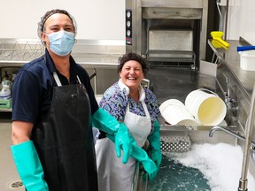 Staff smile as they wash dishes at Calgary Meals On Wheels on Wednesday, November 30, 2022.