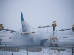 A WestJet Boeing 737 is de-iced at the Calgary International Airport on Tuesday, December 20, 2022. Extreme cold temperatures are forecast for most of the week in the city.