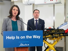 Premier Danielle Smith speaks with Health Minister Jason Copping in the background during a press conference about a new initiative to use alternative modes of transport for non-emergency transfers to the hospital.  The aim is to help free up paramedics and ambulances for emergency calls.  The announcement took place on Wednesday, December 21, 2022, in a training lab at the Cal Wenzel Precision Health building adjacent to Foothills Hospital.