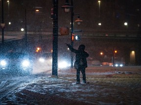 A person hails a taxi as heavy snow falls in downtown Vancouver, late Monday, Dec. 19, 2022. Environment Canada issued a snowfall warning for Metro Vancouver and the south coast of B.C. with 10 to 20 centimetres of snow expected.