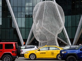 A Checker Taxi taxi moves between cars in traffic in front of the Wonderland Sculpture in downtown Calgary on Thursday, January 26, 2023.