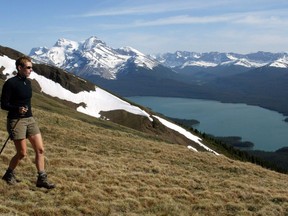 A hiker takes in the snow covered mountains surrounding Maligne Lake in Jasper National Park on June 22, 2002. Environmental groups are welcoming Parks Canada's buyout of two businesses in Jasper National Park's Tonquin Valley, a scenic destination also used by vanishing caribou herds.