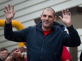 Former Vancouver Canucks' enforcer Gino Odjick gets up out of a wheelchair and waves to hundreds of fans that gathered to support him outside Vancouver General Hospital in Vancouver, B.C., on Sunday June 29, 2014. Odjick announced on the NHL hockey team's website last Thursday that he was diagnosed with AL (Primary) Amyloidosis and could have months or even weeks to live. The condition causes abnormal protein to be produced leading to the hardening of the heart.