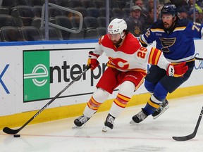Dillon Dube of the Calgary Flames controls the puck against Justin Faulk of the St. Louis Blues in the second period at Enterprise Center on January 12, 2023 in St Louis, Missouri.