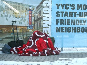 A man is bundled up under blankets and other warm items in East Village in Calgary near downtown on Tuesday, January 24, 2023.