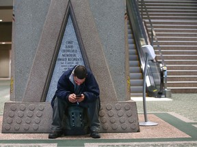 A man utilizes a small ledge as a seat in the main atrium at the Municipal Building in Calgary Friday, January 27, 2023.