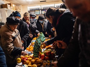 On January 6, local residents gather at a humanitarian aid center in Bakhmut for small cakes and fruit around a table.