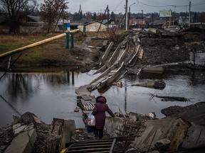 A woman crosses a destroyed bridge in Bakhmut on January 6.  Most of the city's pre-war population of 70,000 had left for safer territory, leaving behind cratered roads and buildings that had been reduced to rubble and twisted metal.