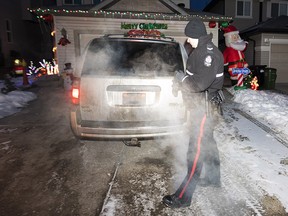 A police officer checks a vehicle left running in an Edmonton driveway on Dec. 7, 2021.