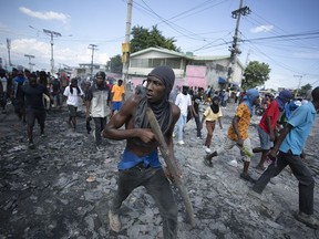 A protester carries a piece of wood simulating a weapon during a protest demanding the resignation of Prime Minister Ariel Henry in the Petion-Ville area of Port-au-Prince, Haiti, on Oct. 3, 2022.