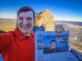 Jeromy Farkas holds a copy of the Calgary Sun atop Mount Yamnuska on January 11, 2023.