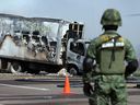 A soldier stands guard near a vehicle that was set on fire by members of a drug gang at a roadblock in Mazatlan, Mexico, on January 5.  Violence broke out after the arrest of drug gang leader Ovidio Guzman.