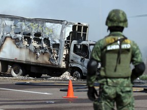 A soldier keeps watch near a vehicle set on fire by members of a drug gang at a barricade in Mazatlan, Mexico, on Jan. 5. Violence erupted after the arrest of drug gang leader Ovidio Guzman.