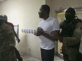 Former Haitian lawmaker Arnel Belizaire is escorted by national police to be presented to the press in Port-au-Prince, Dec. 4, 2019.