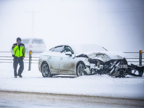 Emergency workers check on one of a dozen vehicles damaged in a pileup on Stoney Trail between McKnight Blvd. and 16th Avenue N.E. after snow flurries swept through Calgary on Tuesday, Feb. 28, 2023. There were no serious injuries in the crash.