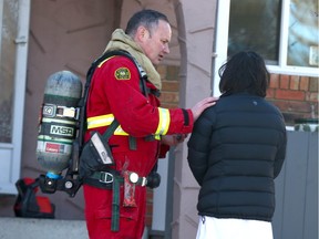 Calgary firefighers and police comfort and speak with a visitor at a fatal fire scene on Penworth Way S.E. in Calgary on Friday, February 17, 2023. A 71 year old man passed away at the scene, one of two fatal fires early on Friday.